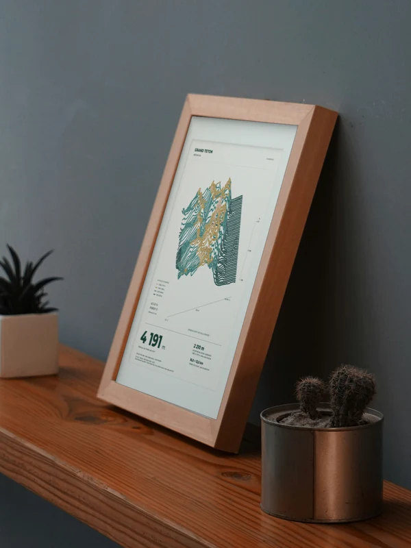La obra Grand Teton integrada digitalmente en un marco, sobre una repisa junto a plantas. El marco y las proporciones son ilustrativos.
